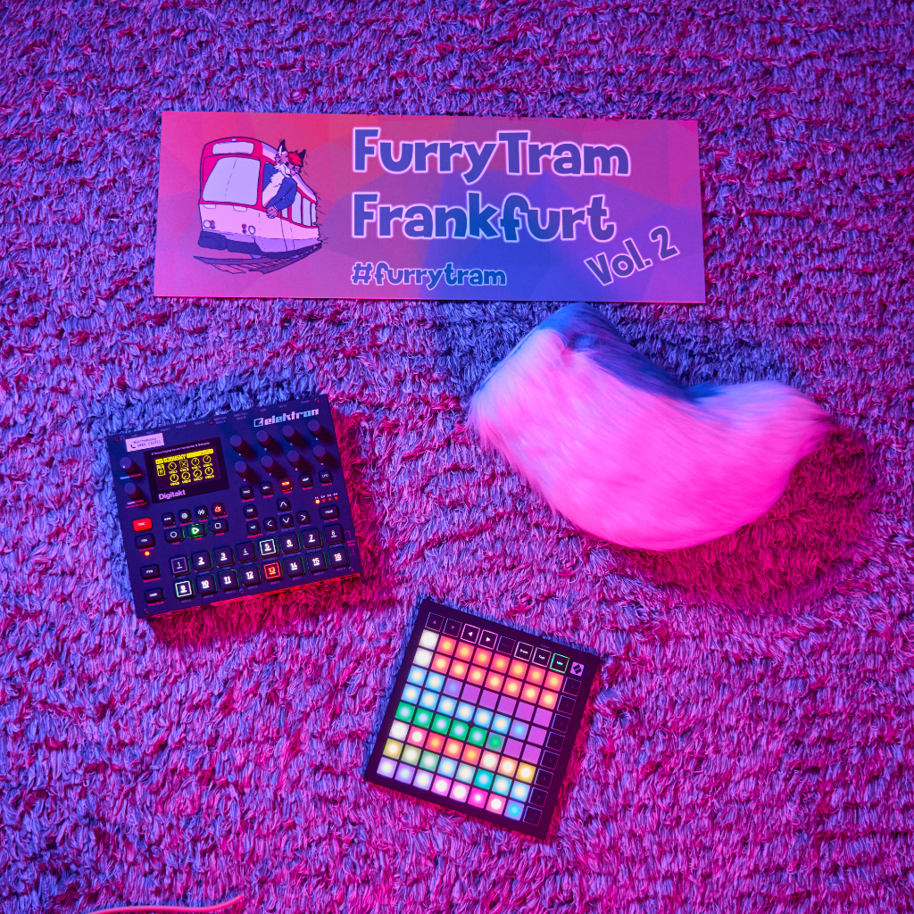 Cover-Bild vom FurryTram DJ-Set. Foto eines flauschigen Teppiches von oben mit pinkem und blauem Licht, auf dem diverse Objekte verstreut sind: Ein Sampler, ein Launchpad, ein Schild aus der Tram mit der Aufschrift "FurryTram Frankfurt Vol. 2" und ein Fursuit-Tail meiner Sona.